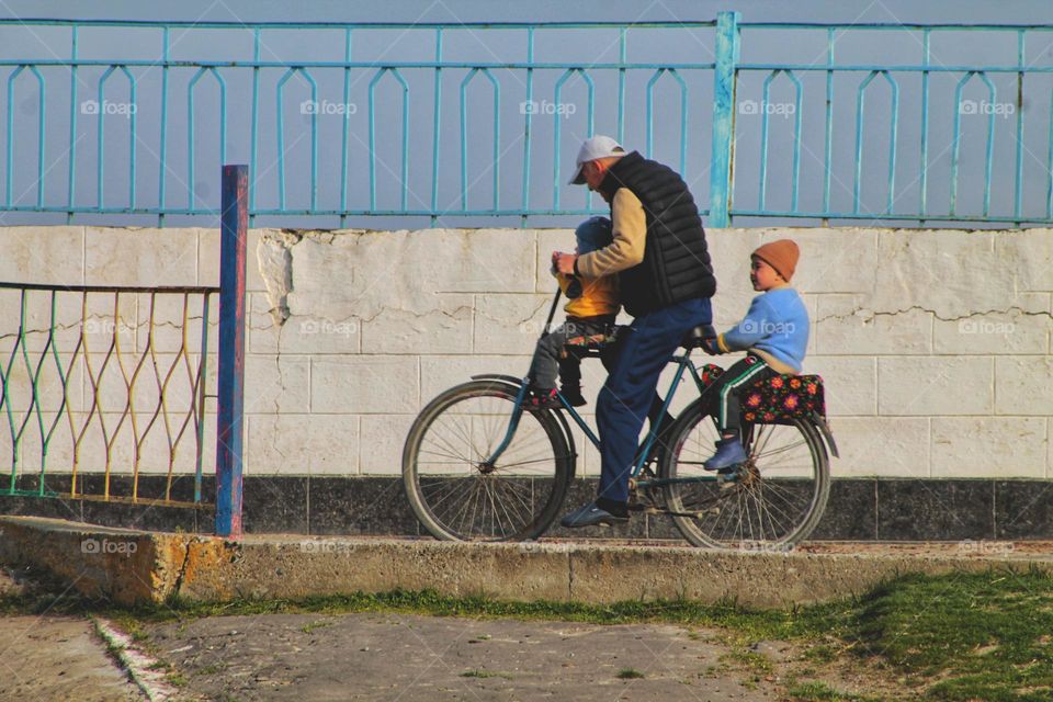 a man carries his two daughters on a bicycle