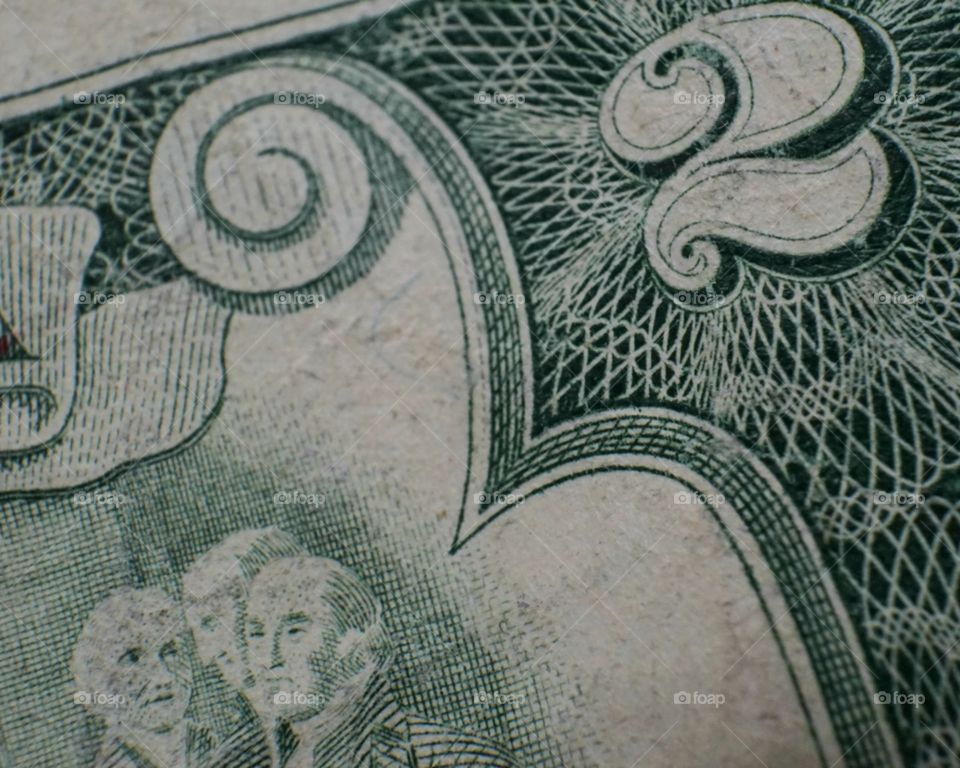 Old two dollar bill close up shows unique design and and faces.