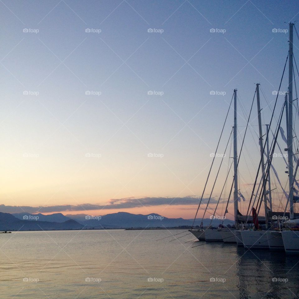 Sailboats in a harbor at sunset in Napflio, Greece