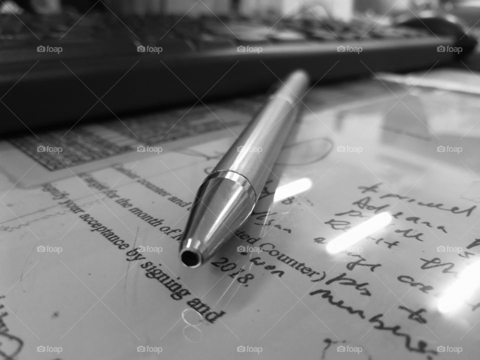 Tip of a pen on a glass panel with a letter below