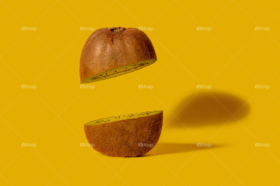 Kiwi fruit sliced on half with one half floating. Creative fruit concept