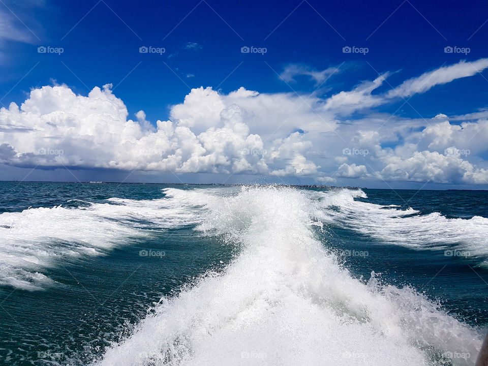 estela de agua creada por un barco haciendo un paisaje de mar y cielo lleno de color y vida con azules increibles acompañado de un día con nubes