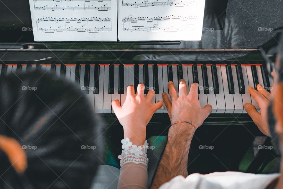 Girl teaches a pupil to play the piano