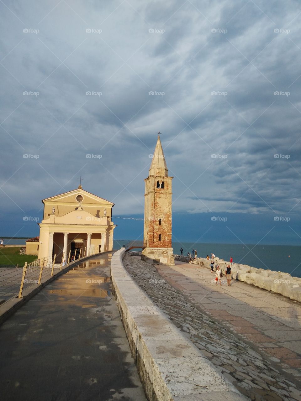 a panoramic view of caorle venice italy madonna dell angelo church and lighthouse bell tower at city seafront rock