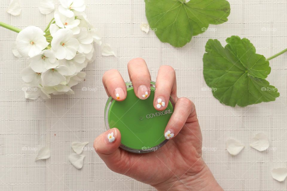 Woman's hand with beautiful manicure is holding a powder case