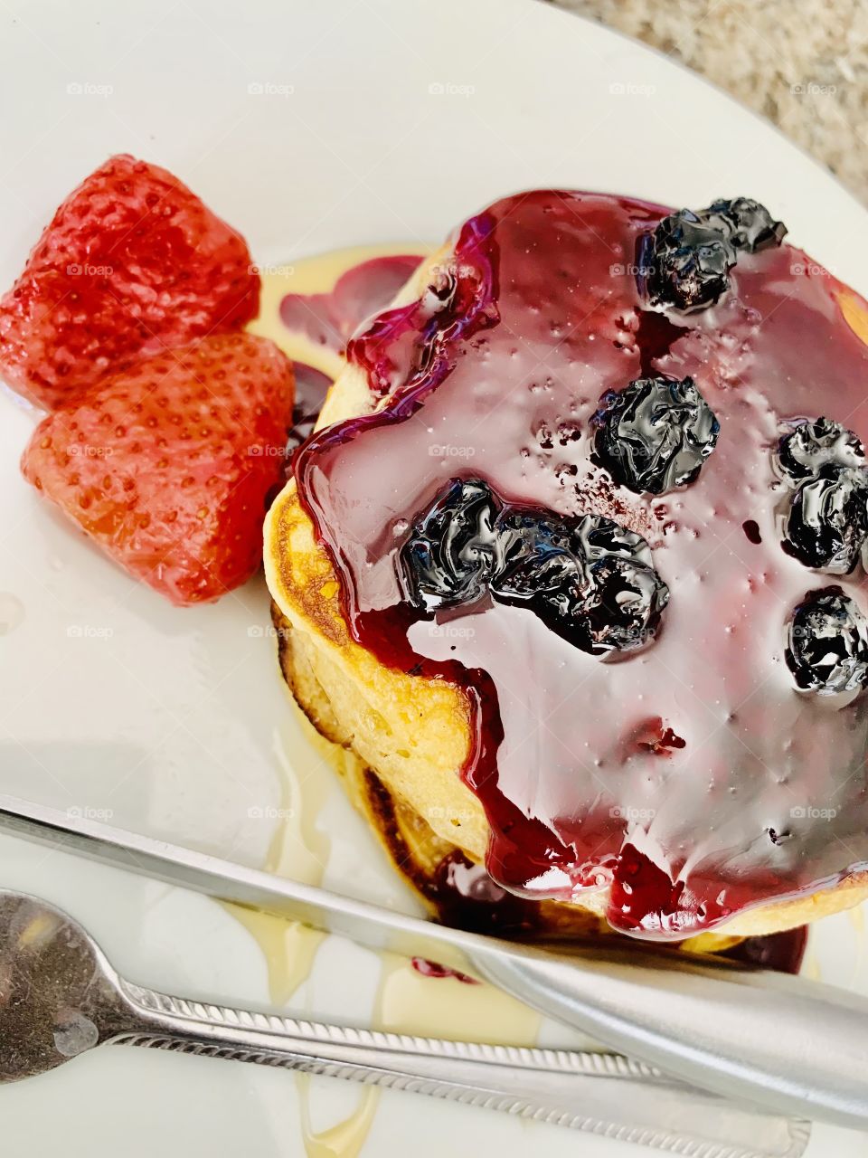 Breakfast today is pancakes with a berries syrup and frozen strawberries on the side.