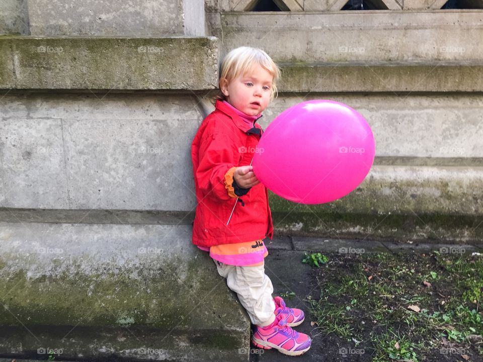 Little girl of two years old holding a pink balloon at Lundagård in Lund Sweden.