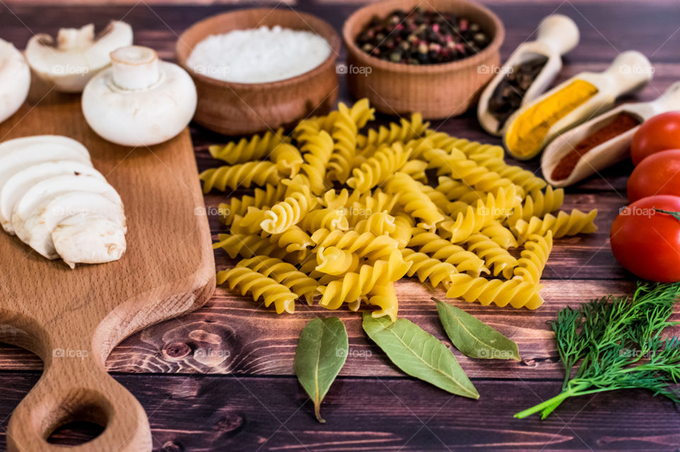 Raw pasta with ingredients and wooden accessories