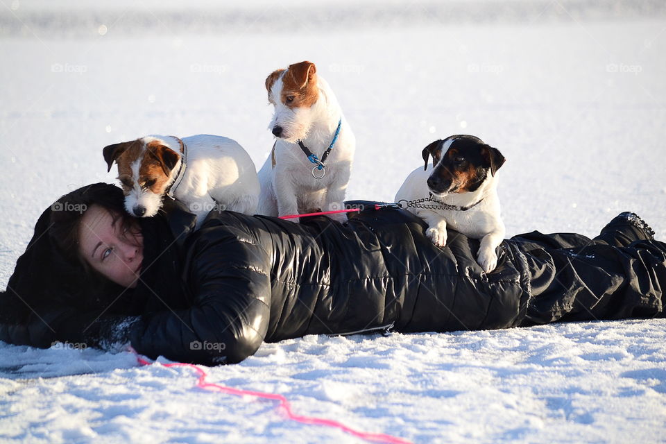 Puppies sitting over the woman lying on snow