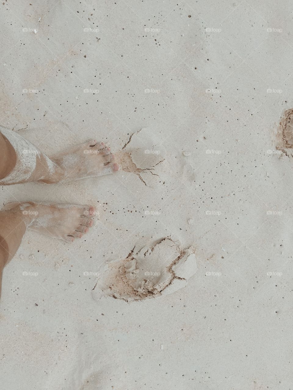 High angle view of feet on white sand beach