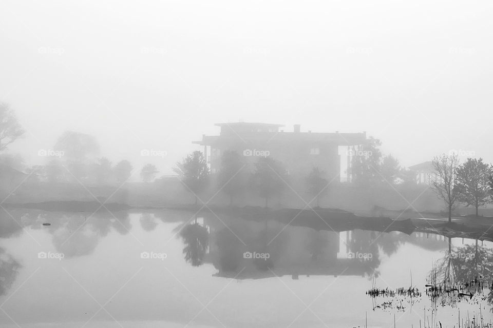 House seen through the fog with its reflection 