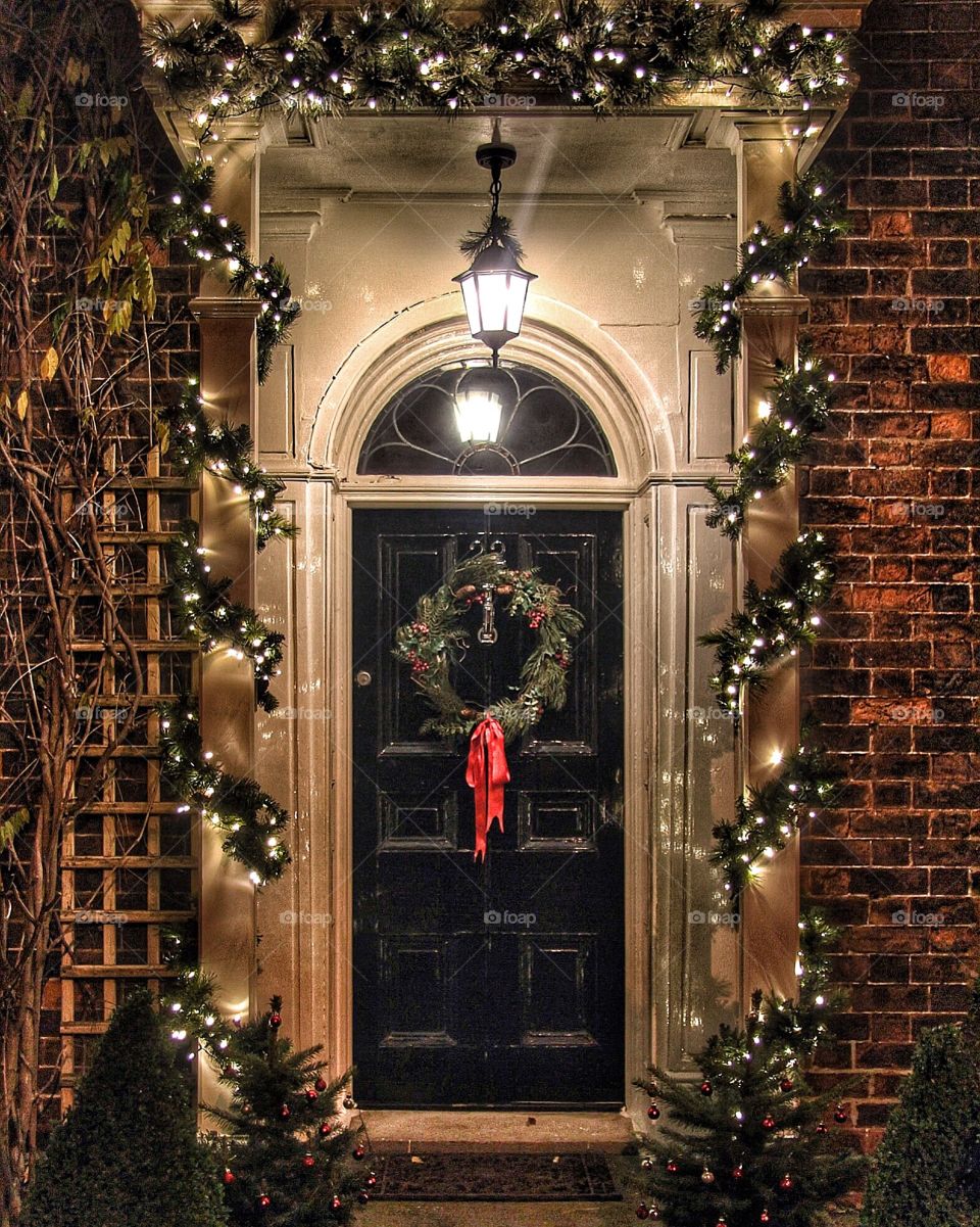 A traditional English doorway decorated with lights and holly ready for Christmas celebrations.