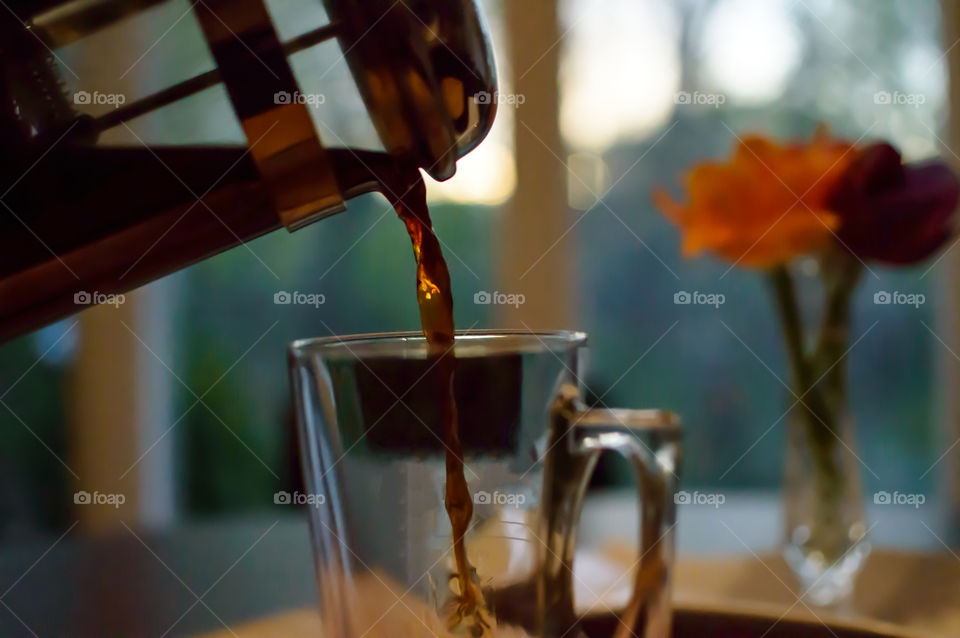 Pouring a cup of freshly brewed coffee from a french press carafe in kitchen at sunset relaxing after work photography 