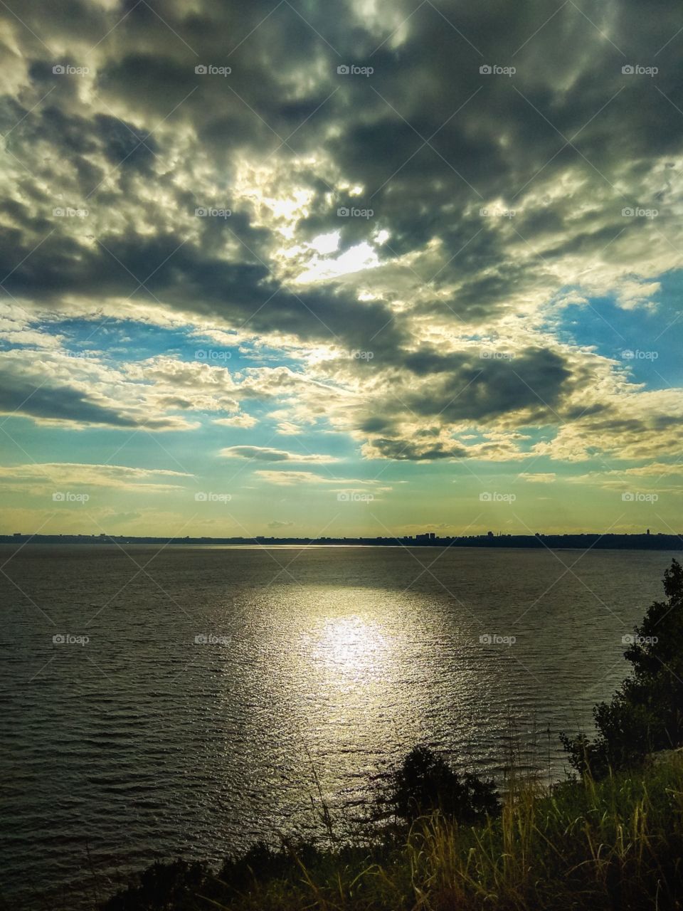 View of a very beautiful sky covered with clouds, through which the light of the sun breaks through, reflecting on the endless expanses of the Volga River (Russia), spread out under all this magnificence, on a cloudy autumn evening