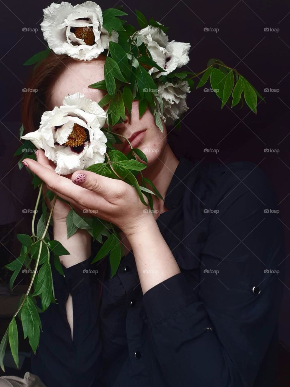 original portrait of a girl in a black shirt holding a white scarf covering her face, dark background