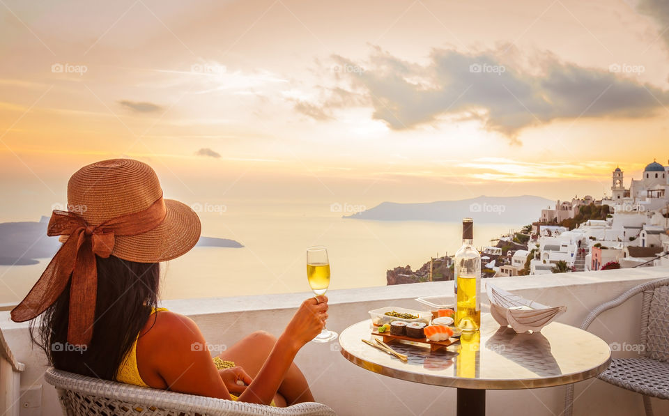 Woman with wine glass enjoying the view of Greece, Santorin