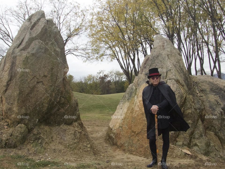 Funky man standing in front of a big rock