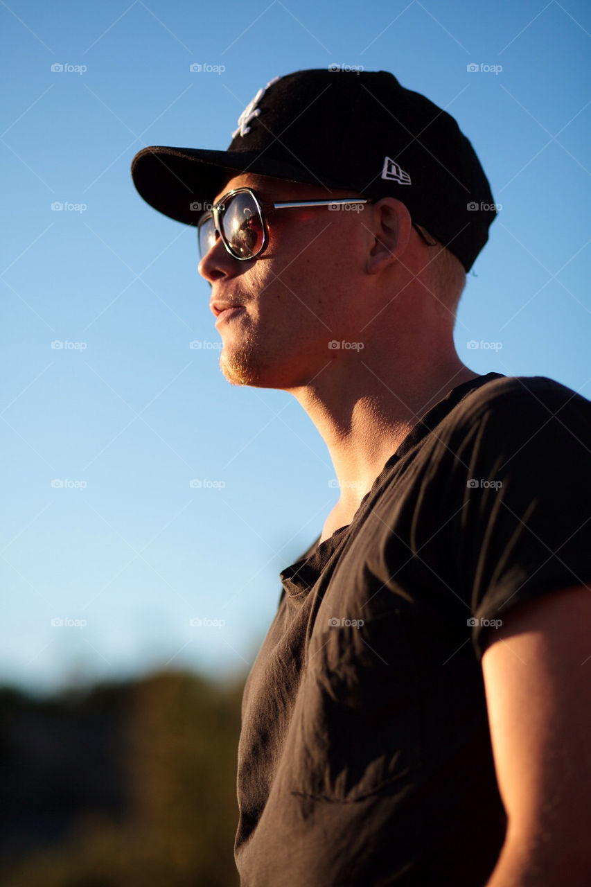 Man looking towards the sun in sunglasses and cap