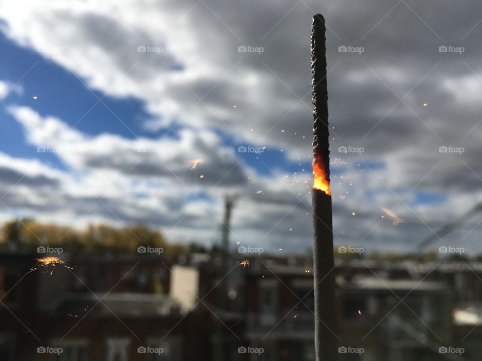 Birthday sparkler burning on a sunny sky and a windy day . The macro picture is a great way to show it 