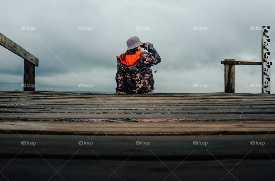 girl watching with binoculars on the pier