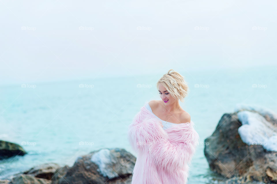 happy girl in pink coat at sea