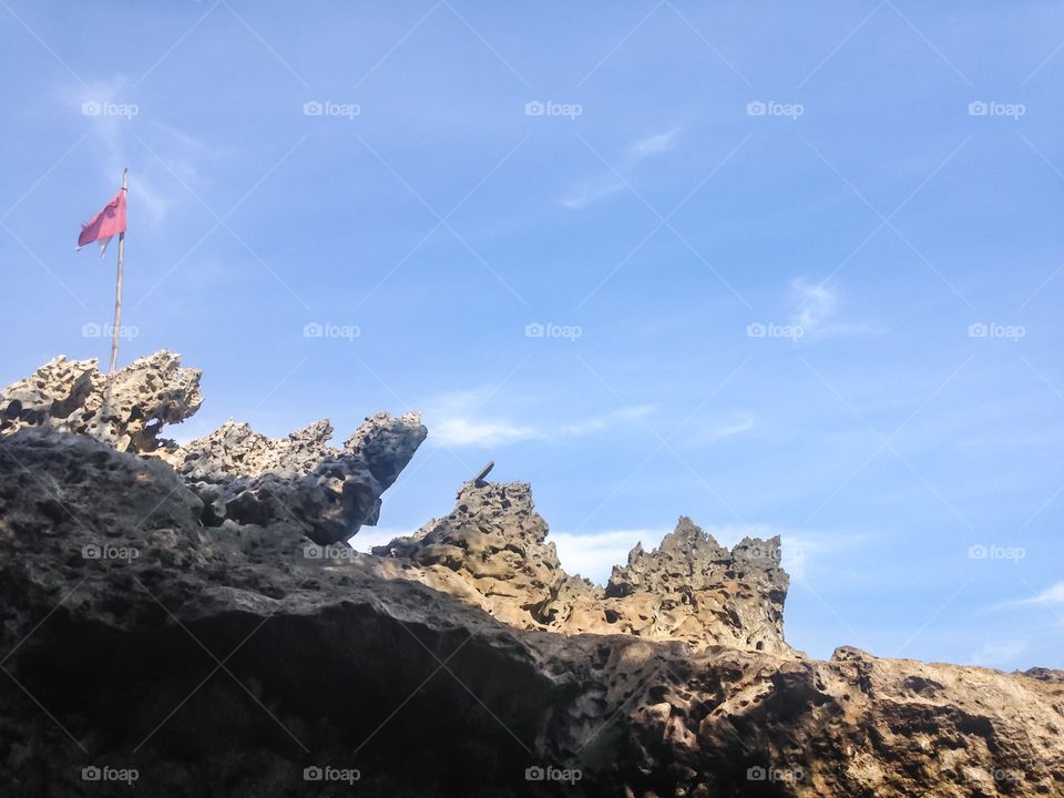 The flag fluttered on the rock by the beach