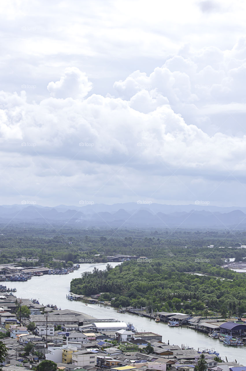 The point of view of Cityscape and a boat parked in Tha Taphao river , Background mountains and  sky at Mutsea Mountain Viewpoint in Chumphon , Thailand.