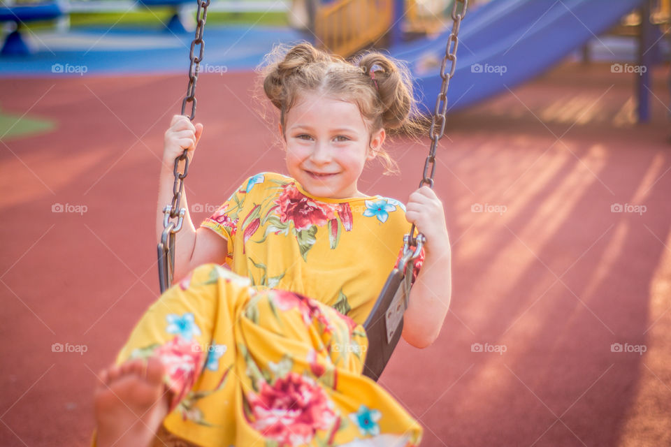 Young Girl Swinging at the Playground in Yellow Floral Dress 2