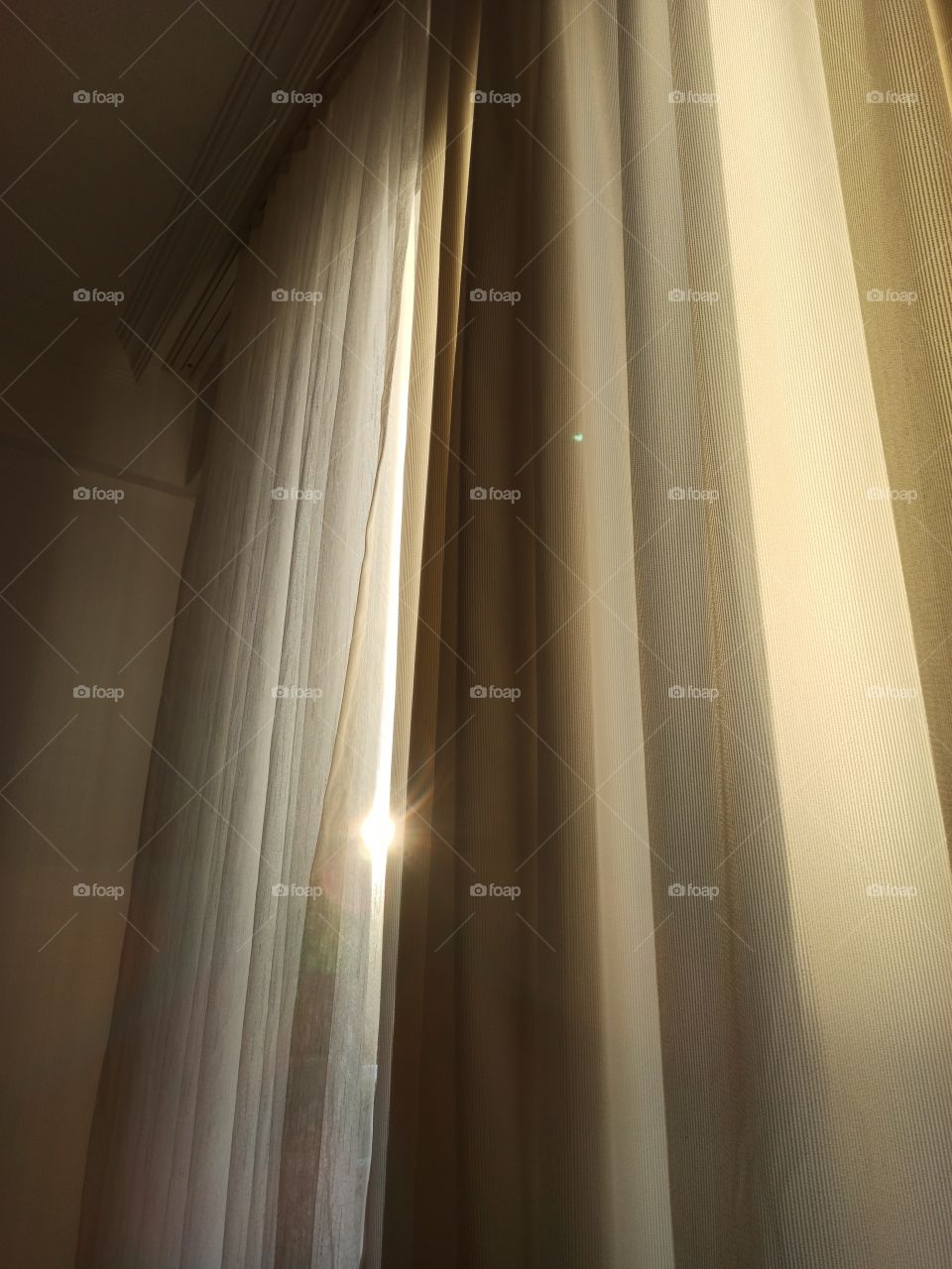 A morning photo of naturally with sunlight illuminated curtains with visible sun in between