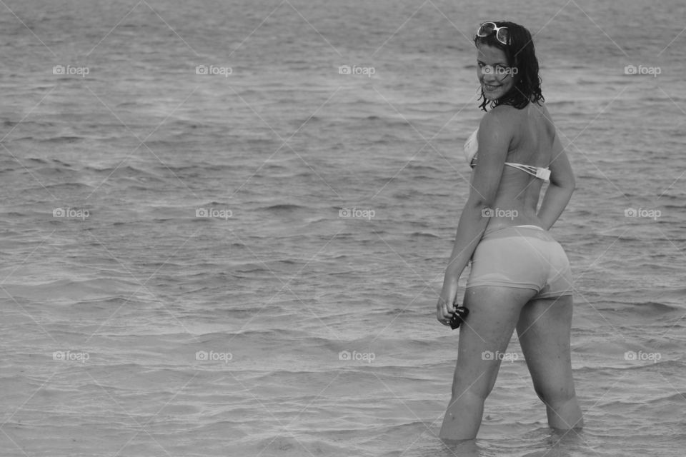 Happy young woman standing in water at beach