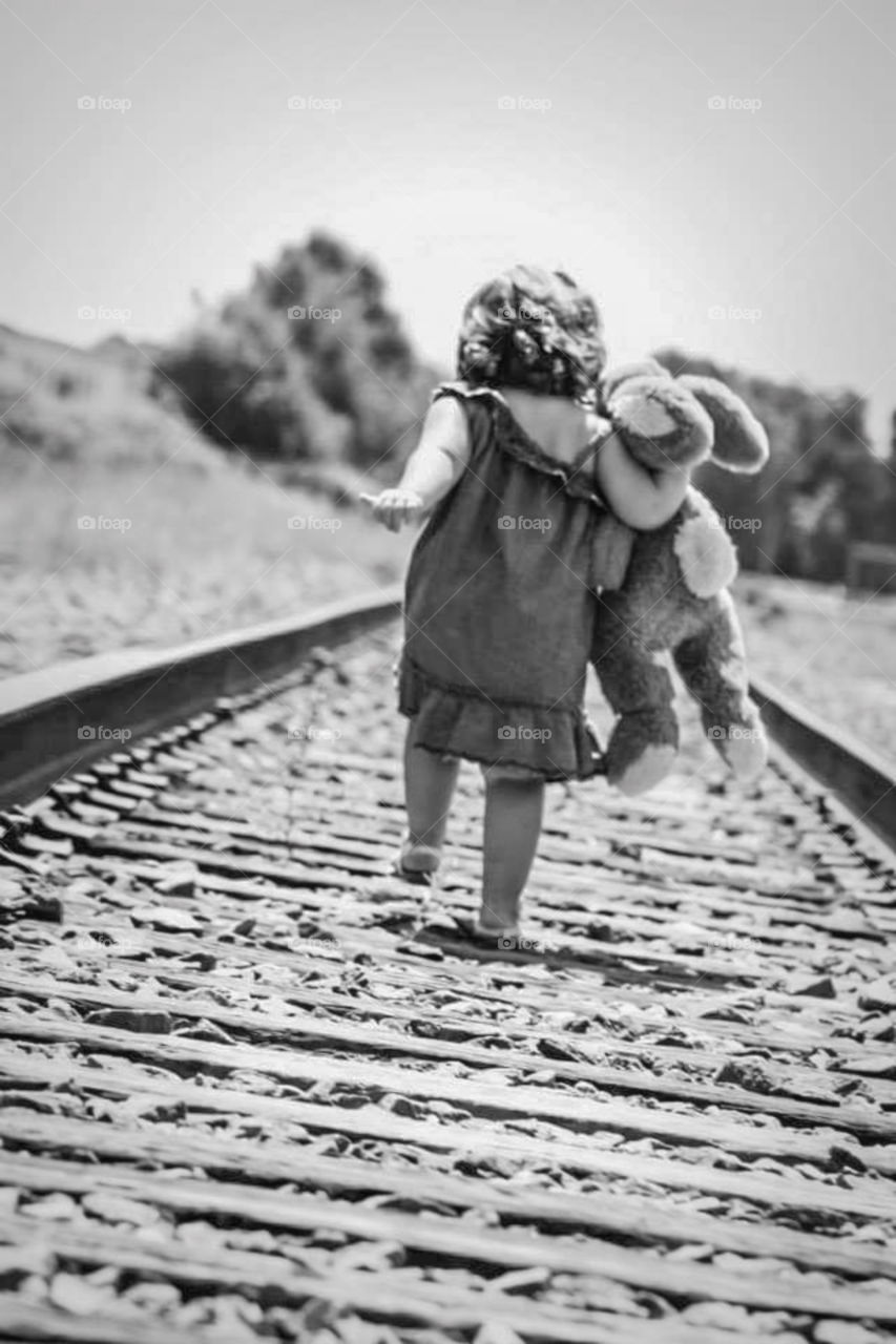 Little Girl with stuffed bunny rabbit running down train tracks. black and white. vintage