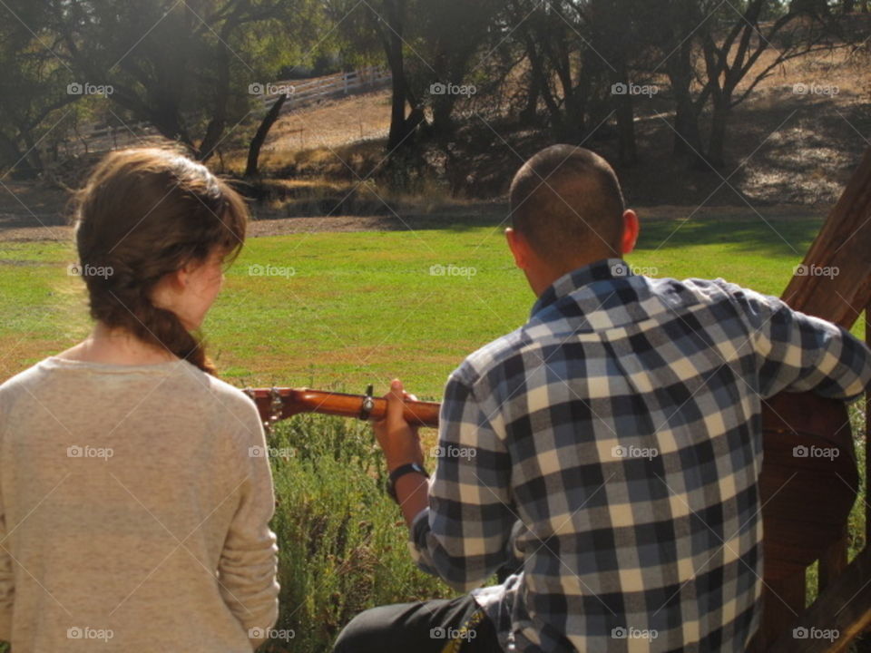 Rear view of man playing guitar sitting with woman