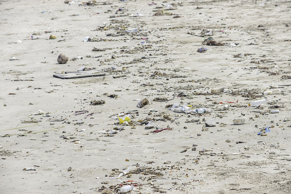 Waste bottles, glass and bag made of plastic on the beach.