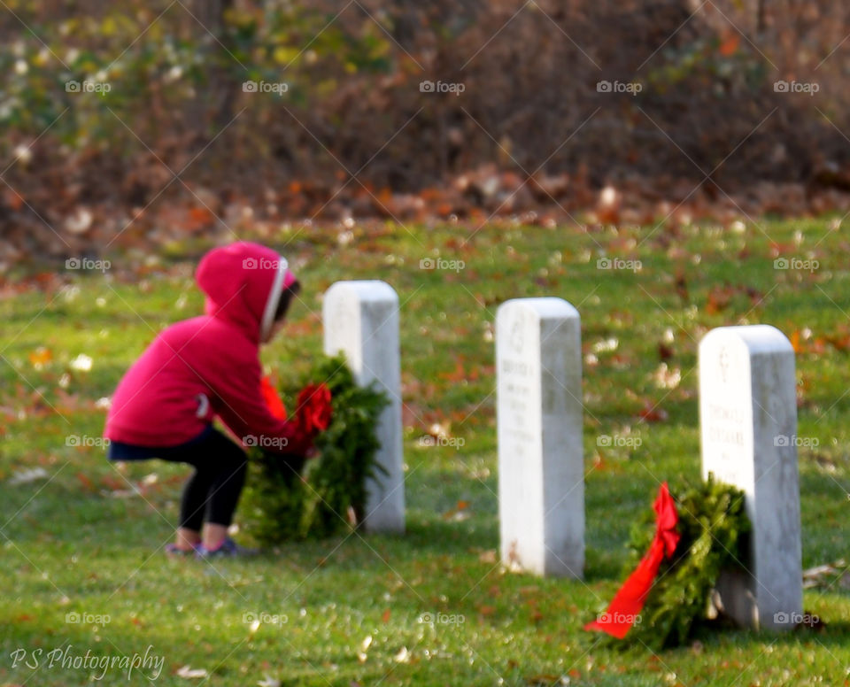 Wreaths Across America. Child laying a wreath in Arlington,  VA