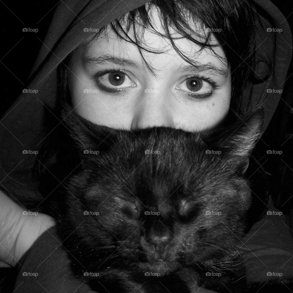 girl with hoodie cuddling with black cat