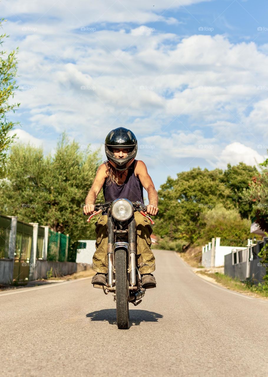 Man rides a motorcycle on a road on a sunny afternoon 