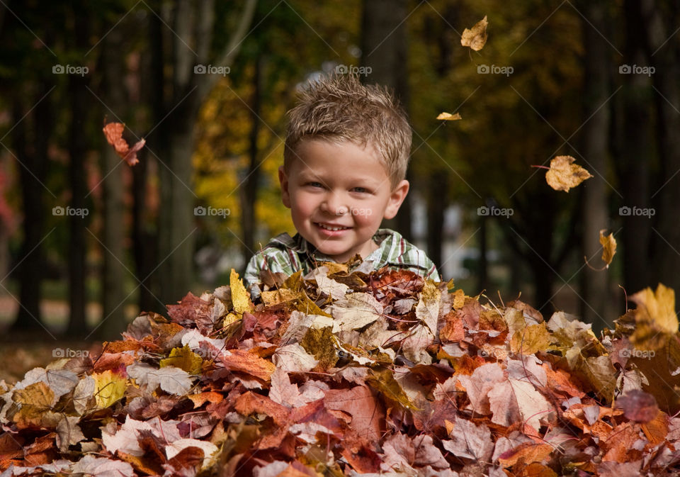 Portrait of a happy boy with dry autumn leaf