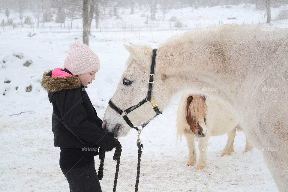 Girl standing with horse on snowy landscape