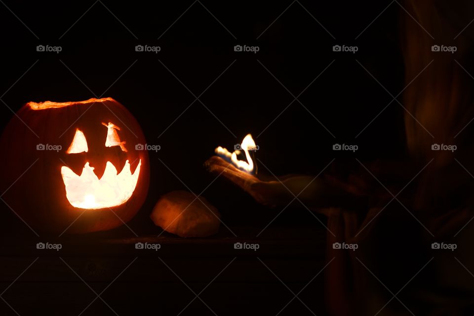 My Flame Buddy; Woman holding a flame “creature” by a lit pumpkin