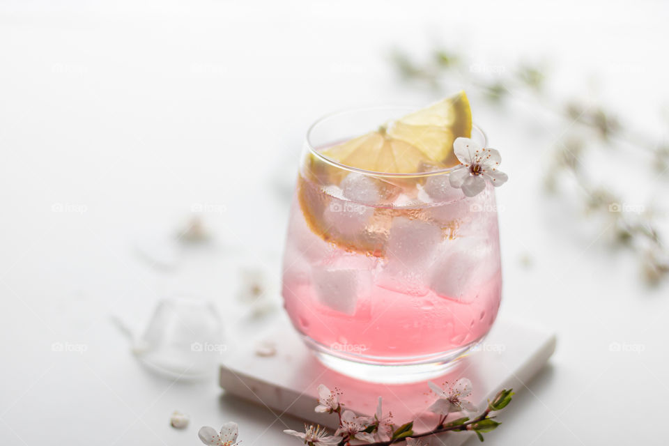 Rose coloured cocktail drink decorated with white flower and a slice of lemon. Gin tonic Cocktail 