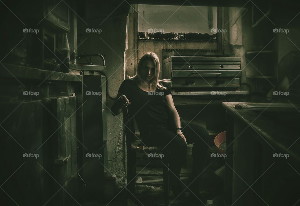 Woman sitting on chair in abandoned house