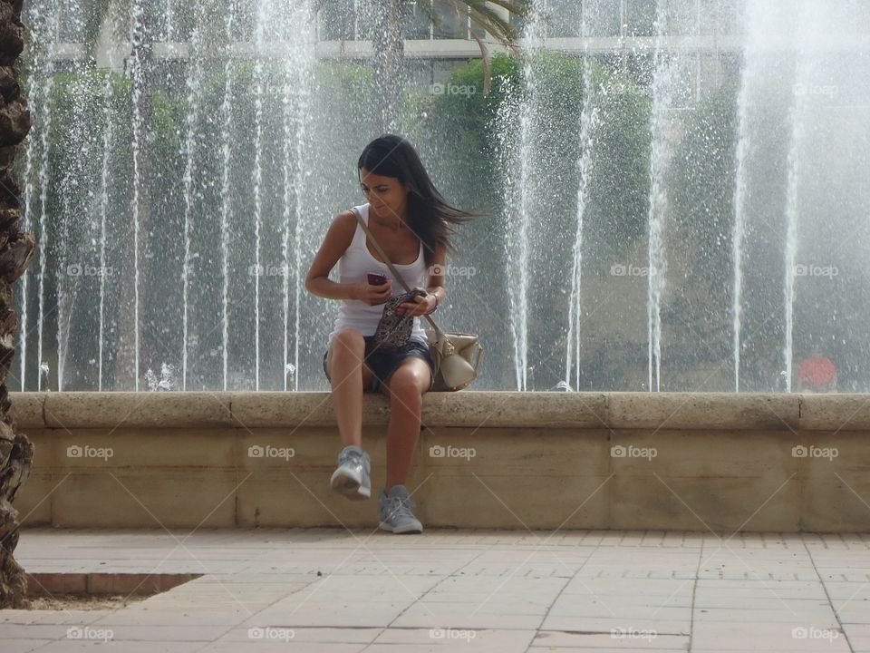 At the fountain. A woman in front of at an big fountain