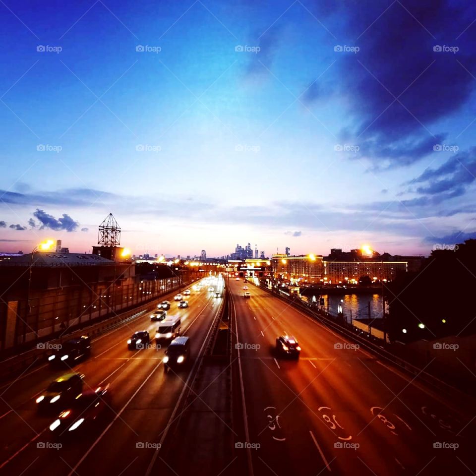 Rush hour traffic on highway at sunset, multiple lines on the road and car lights