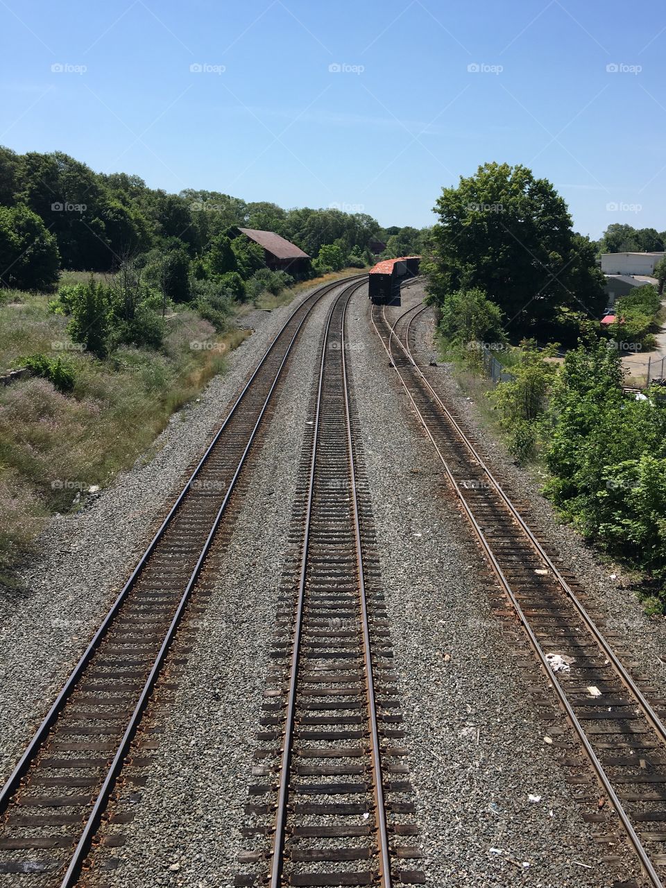 Three railroad track heading towards passenger station! 3rd rail has open top rail cars full of trash, covered! In distance.