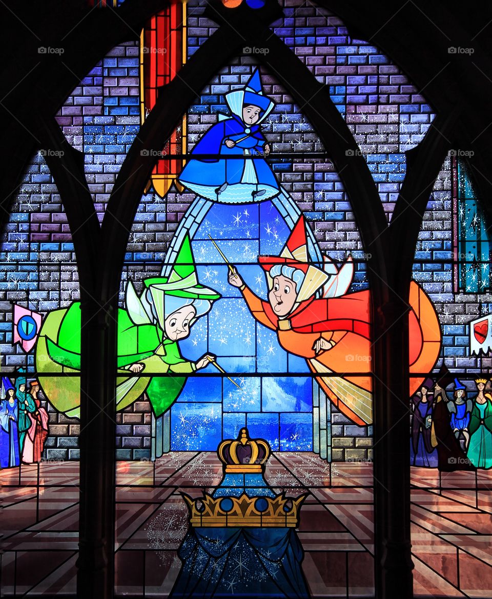 Stain Glass Fairy Godmothers. A stained glass window depicting the story of Sleeping Beauty with the three fairy Godmothers casting spells and magic.