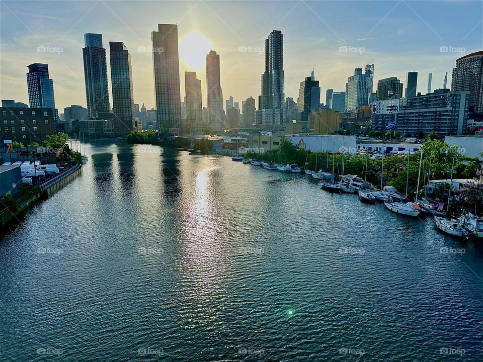 This is “Newtown Creek”, an ocean inlet of the “East River” seen from the “Pulaski Bridge” that connects LIC, Queens to “Greenpoint”, Brooklyn. In the distance across the water we see the “Manhattan” skyline. 2024. Hypnotic Productions