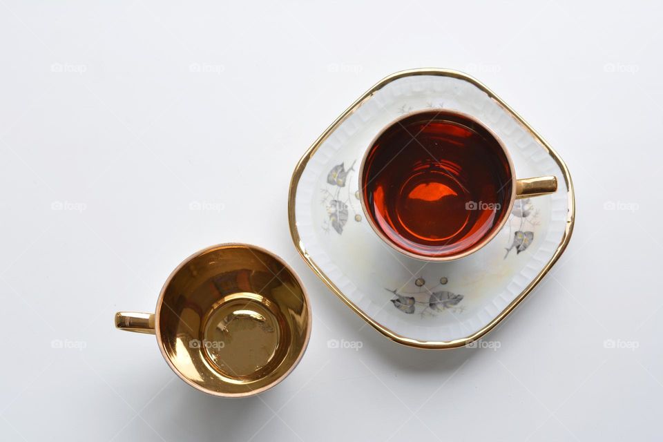 cup of tea gold top view on a white background, beautiful texture