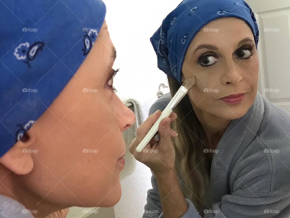 Woman applying makeup in a mirror.