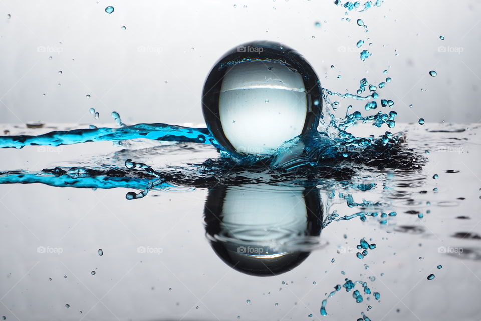 Crystal sphere in blue water. Reflection the scene with a glass.