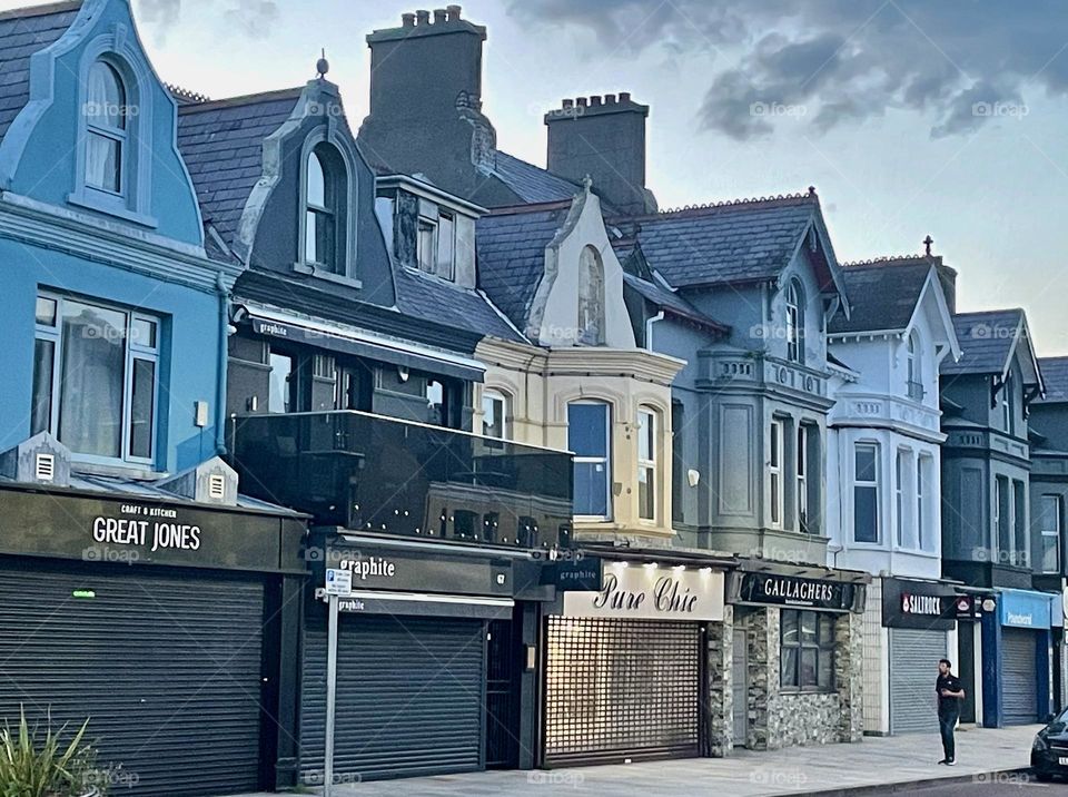 The summer solstice mutes the closed up row of painted shops in Newcastle, Northern Ireland.